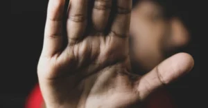 essoa desfocada com a palma da mão estendida em sinal de pare contra a violência doméstica. Foto ilustrativa referente ao caso em que um homem foi preso por agredir a mãe em Arapongas.