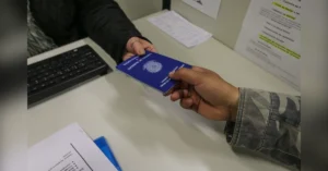 Mãos de duas pessoas trocando o documento da Carteira de Trabalho durante seleção para vagas de emprego em Maringá na Agência do Trabalhador.